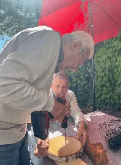 Helfer unterstützt einen Senior bei einer handwerklichen Tätigkeit im Garten.