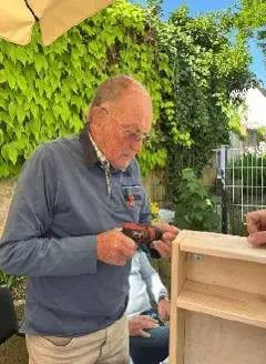 Senior arbeitet konzentriert an einem kleinen Holzprojekt im Freien.
