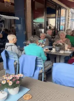 Seniorinnen und Senioren sitzen gemeinsam an einem Tisch und verbringen Zeit miteinander.