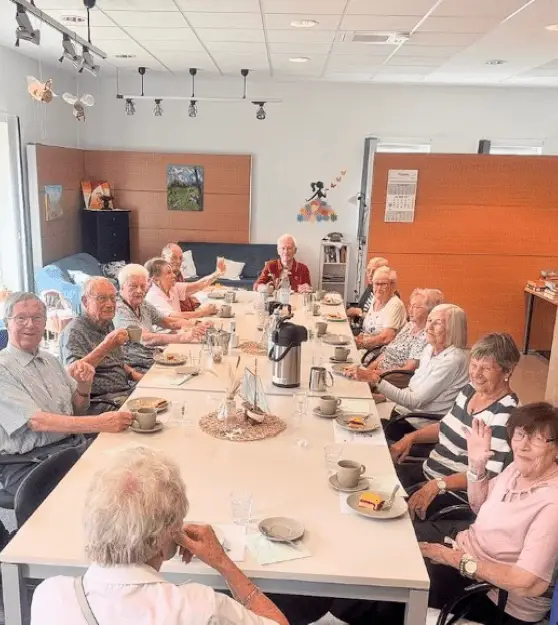 Seniorinnen und Senioren sitzen gemeinsam an einer festlich gedeckten Tafel in der Tagespflege.