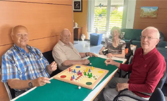 Seniorinnen und Senioren sitzen gemeinsam an einem Tisch und beschäftigen sich mit einem Gesellschaftsspiel.